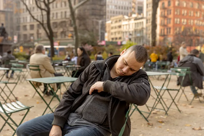 An exhausted man resting his head against his arm outdoors