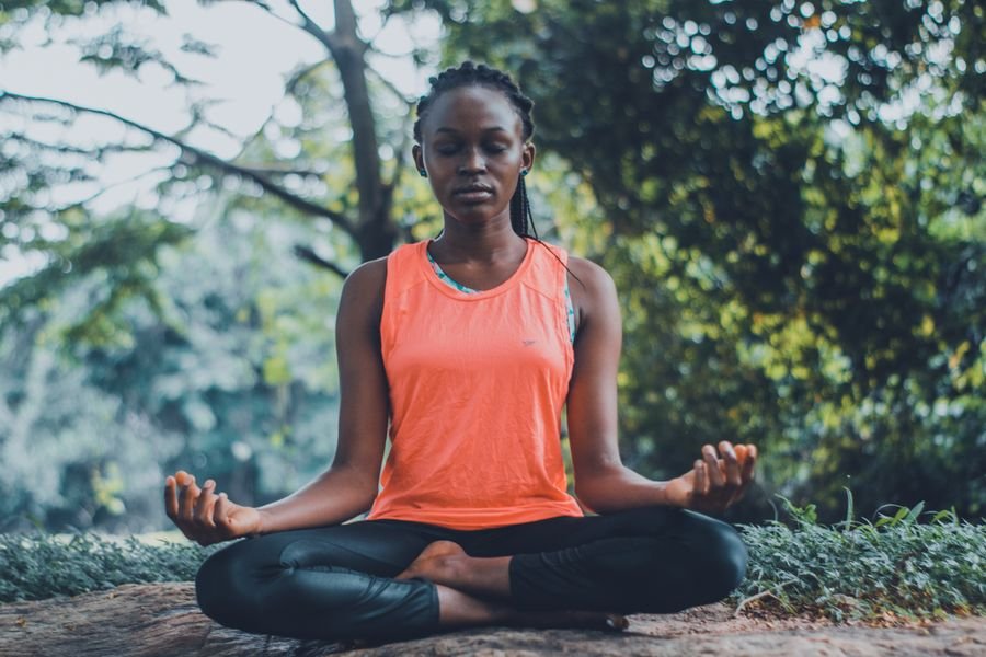 A woman meditating cross-legged outdoors among trees