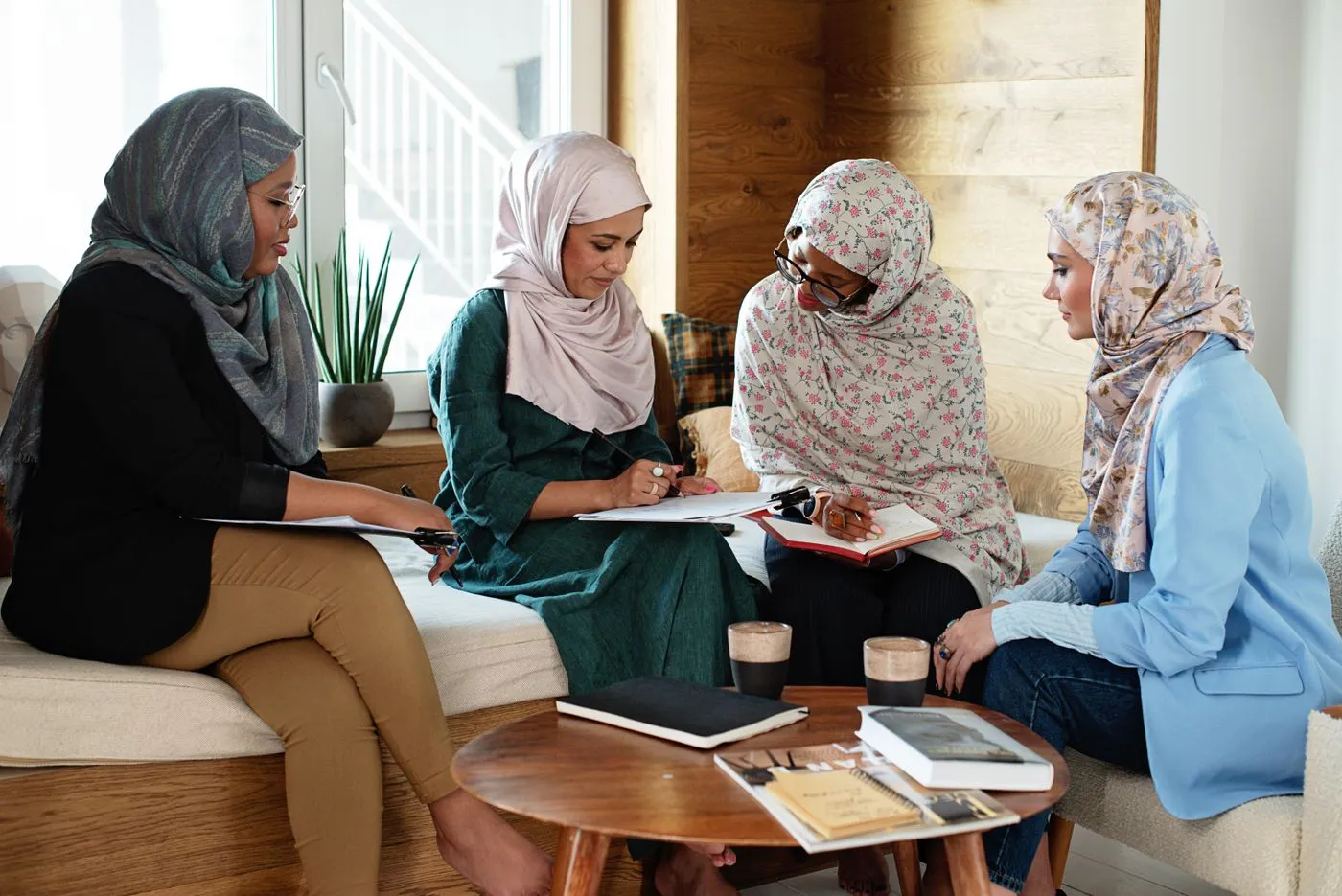 Four women sitting together around a low table, sharing notes and ideas.